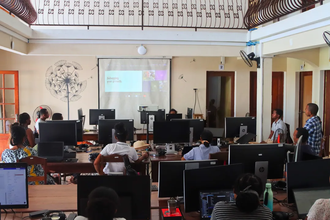 Onja Developers attending a remote technical talk projected at the front of a classroom in Antananarivo.